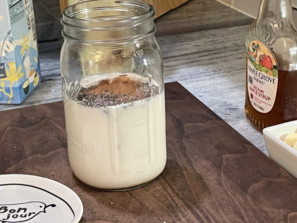 pour oat milk, chia seeds, vanilla extract, cinnamon, and maple syrup into a large mason jar.