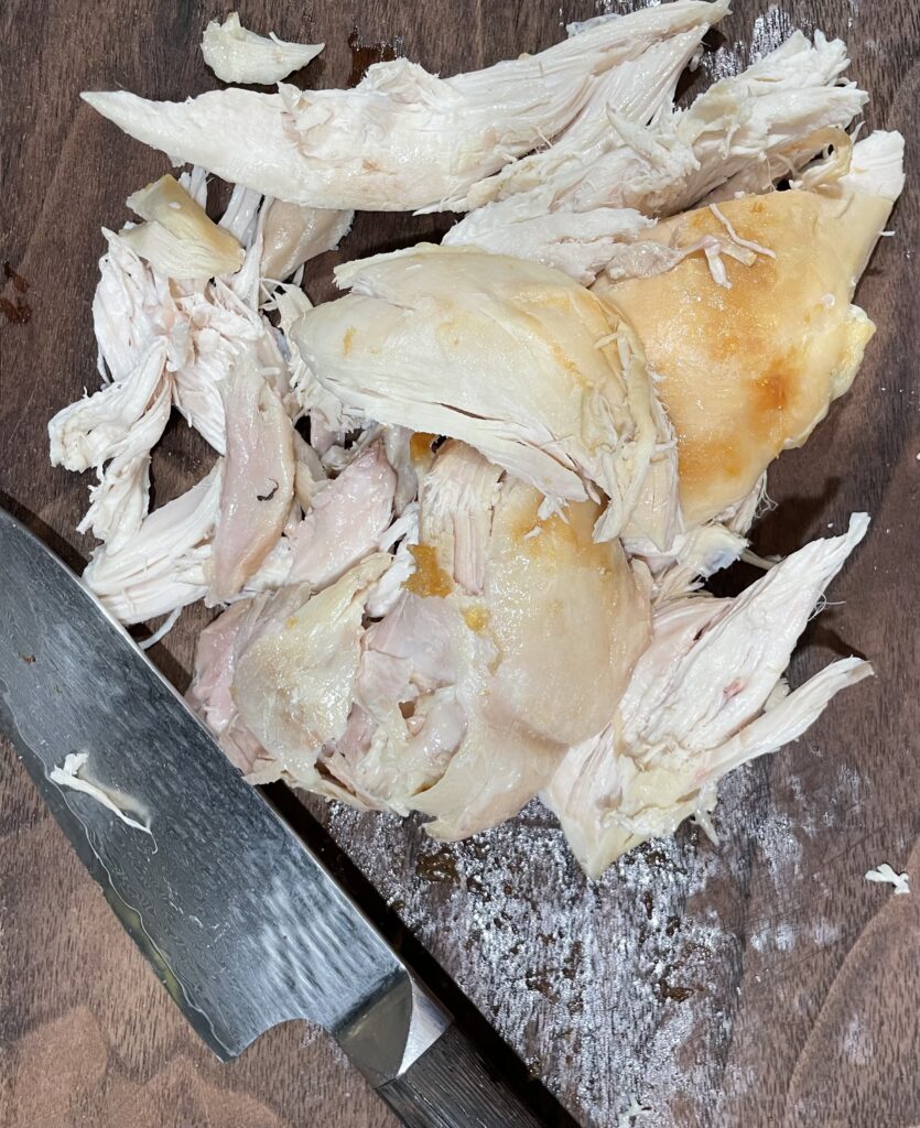 Pieces of White and Dark Chicken on Cutting Board. Knife next to the chicken.