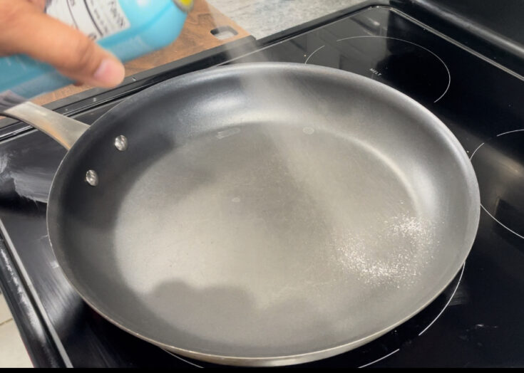 Spraying cooking spray onto frying pan