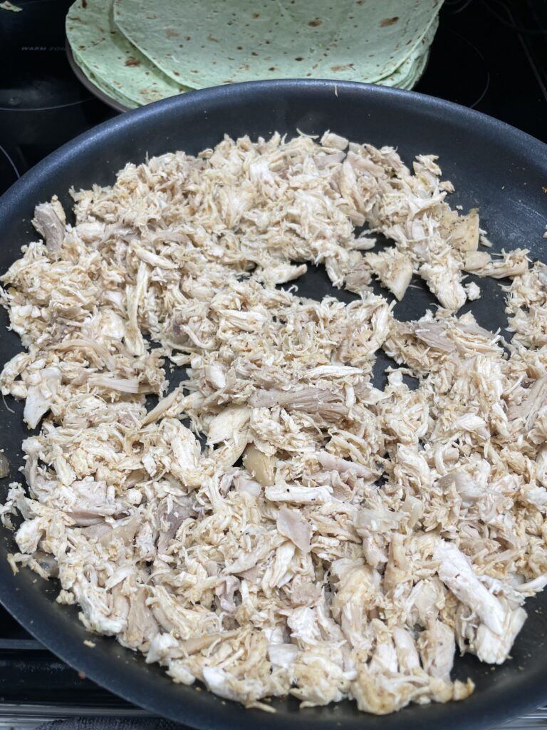 In a pan the chicken broth, spices mixture and the shredded chicken are all combined.