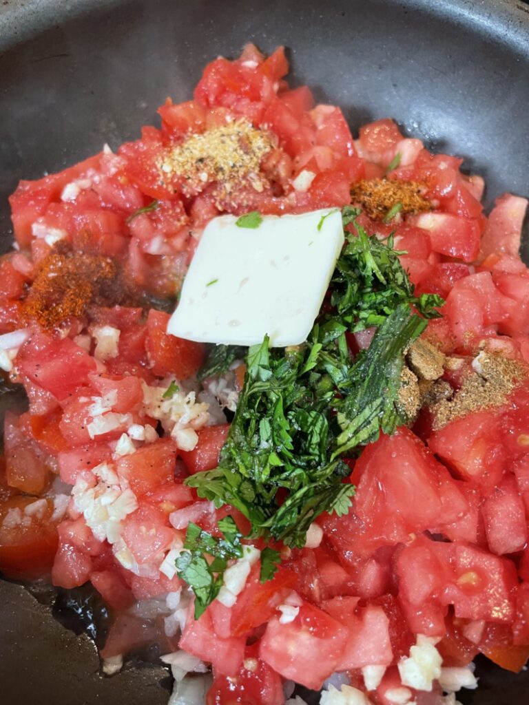 Guiso: Chop tomatoes, onions, garlic, and cilantro, Place in a medium saucepan on the stove and add a little olive oil and butter.