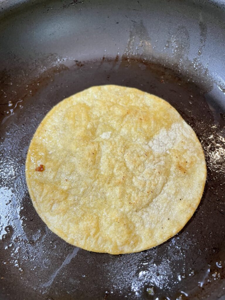 Slightly toasted corn tortilla on a 10 inch pan. 
